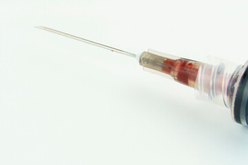 Syringe with a little blood on white background. Selective focus. Macro.