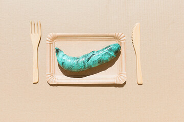 Banana wrapped in polyethylene plastic on the beige paper background. Immature, tasteless or...