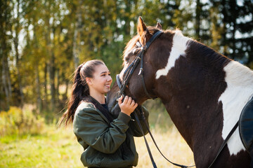 Fototapeta premium The owner of a horse strokes and caresses her horse on an autumn day on the farm