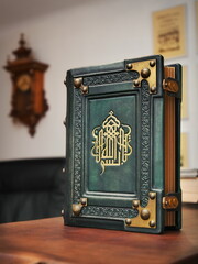 Aged green leather book with gilded calligraphy on the front cover captured in stand up position....