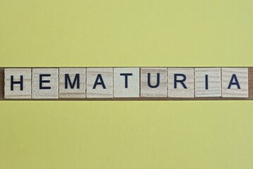 word hematuria made from wooden letters lies on a yellow table