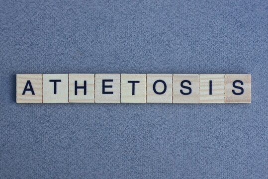 text the word athetosis from brown wooden small letters with black font on an gray table