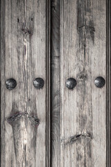 Obraz premium Black and white antique wooden door with nails and knots. Rustic and retro old door full of knots and scratches. Vintage wood texture surface, wood vein. Pareidolia, faces in wood grain.