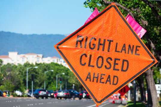 Right Lane Closed Ahead warning road sign on wide city street in urban neighborhood.