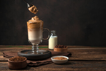 Coffee drink and spoon with coffee foam on a brown background with ingredients.