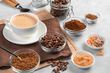 Coffee cup and different types of coffee and sugar on a gray background.