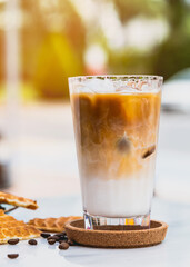 Refreshing iced latte coffee in a glass with heart waffles and coffee beans
