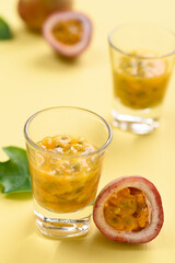 Fresh passion fruit juice in glass on yellow background