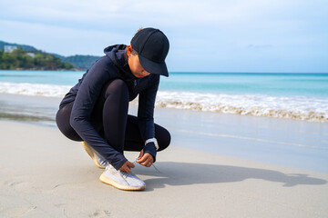 Confidence Asian woman in sportswear do sport training jogging on tropical beach in summer morning. Healthy female athlete workout fitness running on the beach. Outdoor activity lifestyle concept.