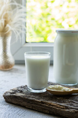 Kefir grains in wooden spoon with glass of kefir drink, healthy fermented probiotic cold dairy drink