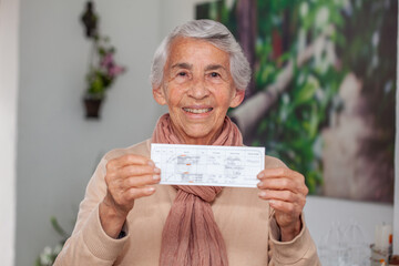 Senior woman at her home holding her vaccination certificate after getting the Covid-19 vaccine at...