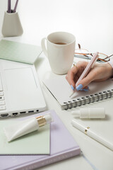 Female hands working on laptop and accessories. Office white desktop, flat lay. Remote working from home. Freelancers laptop, cup of coffee, spectacles. Concept of distance learning, isolation, female