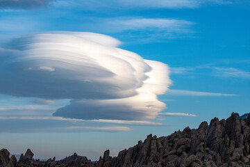Skyline view of lenticular cloud, mountains, rocks. Alabama Hills, California