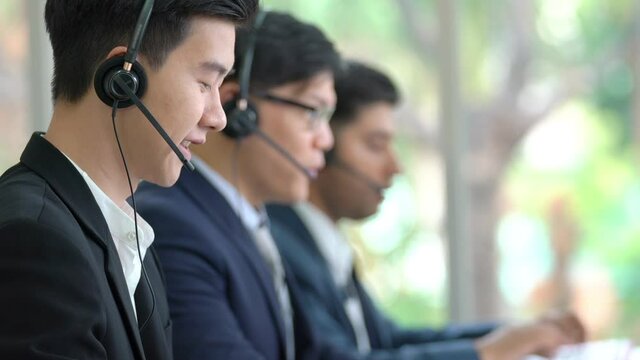 Diversity male customer service call center helpdesk team wearing headset speaking video call for online consulting and support client. Businessman working telesales marketing communication in office.