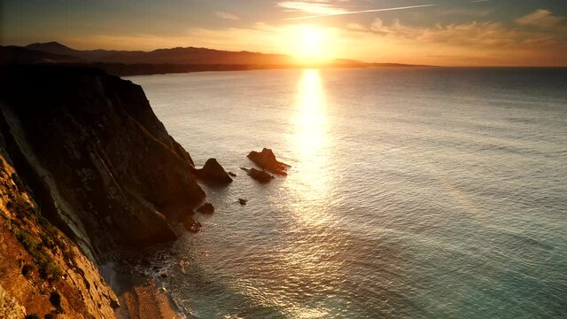 Sunset over rocky cliffs at Asturias coast in north Spain. View from Faro de Cabo Busto. Tourist attraction, place to visit.