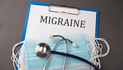 Folder with paper text MIGRAINE , on a table with a stethoscope and medical masks, medical concept.