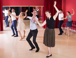 Adult dancing couples enjoying latin dances in modern studio