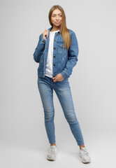 girl in a denim jacket and blue denim pants on a white background