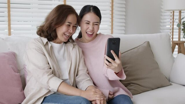 Asian attractive beautiful two people asia young lady girl use mobile phone take photo picture video overjoy sit at home sofa couch have good time day together quarantine in mum healthy health care.