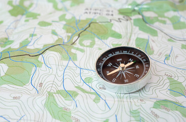 Compass on a physical map, with green details. Travel, exploration and adventure concept.