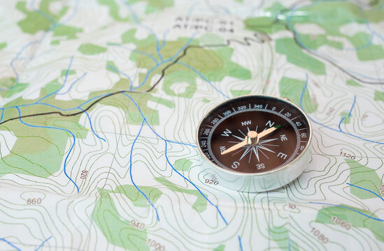 Compass on a physical map, with green details. Travel, exploration and adventure concept. © Marcio