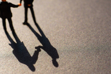 Silhouettes of two businessman, probably men, shaking their hands as a sign of an agreement or...