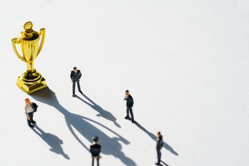 Silhouettes of five businessman and gold Trophies . The meeting takes place on floor  during the warn sunset.