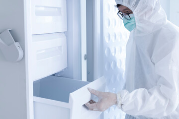 A laboratory technician opening a low temperature freezer. - obrazy, fototapety, plakaty