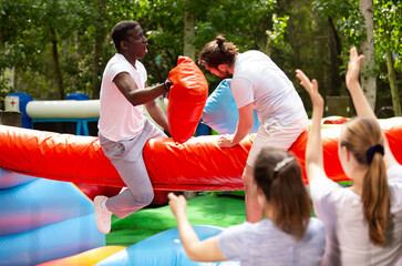 Cheerful pillow fight sitting on a log in an amusement park
