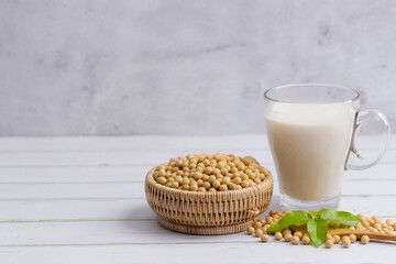 Soy and soy milk in a glass with soybeans in wooden bowl background