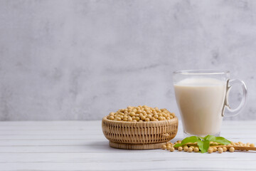 Soy and soy milk in a glass with soybeans in wooden bowl background