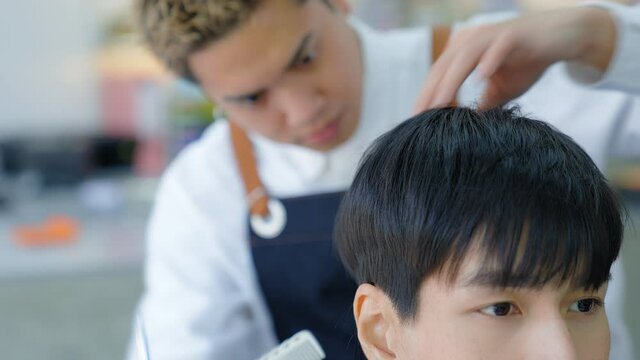 The barber is checking the customer's hairstyle after the cut.. Professional hairdressers to design hair for costomer. Beauty salon or barber shop business concept.