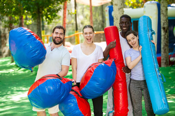 Portrait of happy friends with inflatable logs and pillows at an amusement park - obrazy, fototapety, plakaty