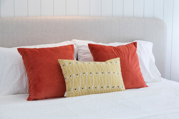 Red and yellow cushions are placed on the bed in a bedroom.