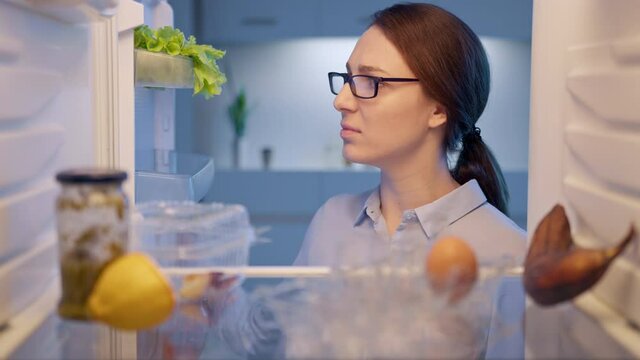 Hungry woman opening fridge looking inside searching for food and disappointed, but the problem can be solved! Online ordering food delivery