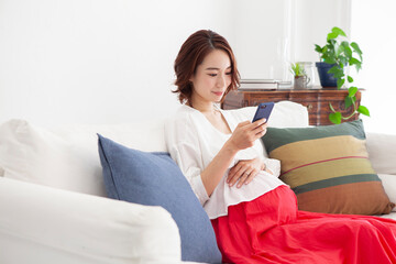 スマートフォンを使っている妊婦の女性