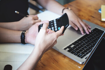 vintage tone effect with business man using calculator to calculate budget  and partnership using computer at work