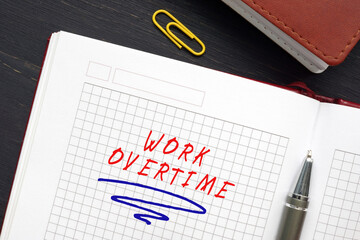 Financial concept meaning WORK OVERTIME with phrase on the piece of paper. Overtime refers to any hours worked by an employee that exceed their normally scheduled working hours.