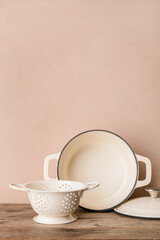 Cooking pot and colander on color wooden background