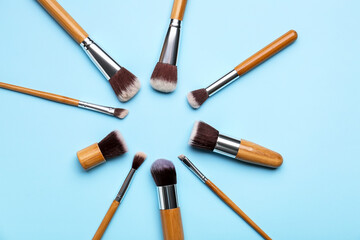 Frame made of makeup brushes on color background