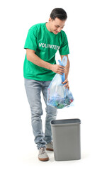 Male volunteer putting garbage in trash bin on white background