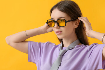 Beautiful young woman with stylish sunglasses on color background