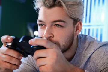 Young man playing video game at home late in evening. Concept of addiction