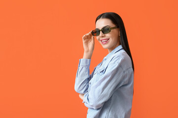 Beautiful young woman wearing stylish sunglasses on color background