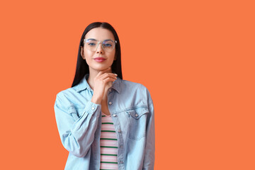 Beautiful young woman wearing eyeglasses on color background