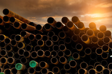 Pile of old rusty round metal industrial pipe. Steel pipe stack during sunset. Industrial material....