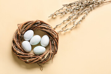 Willow branches and nest with eggs on color background