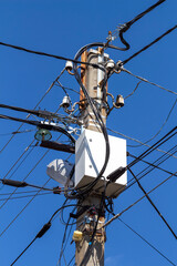 Electrical wires and boxes with electrical equipment on a concrete pole.