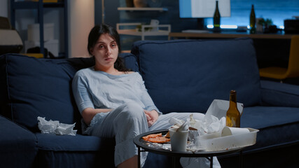 Fototapeta premium Traumatised, frustrated depressed woman looking at camera sitting alone on sofa thinking at loneliness feeling emotionally unstable, lonely desperate vulnerable suffering from anxiety, chronic disease