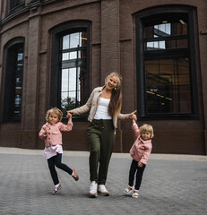 young beautiful mother with long hair with children on walk in street happiness joy fun motherhood